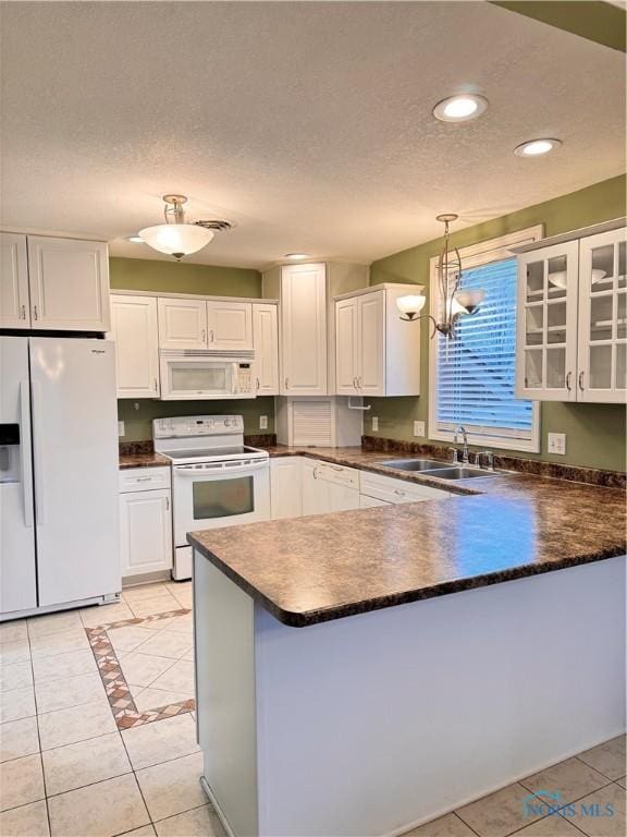 kitchen with sink, white cabinets, hanging light fixtures, and white appliances