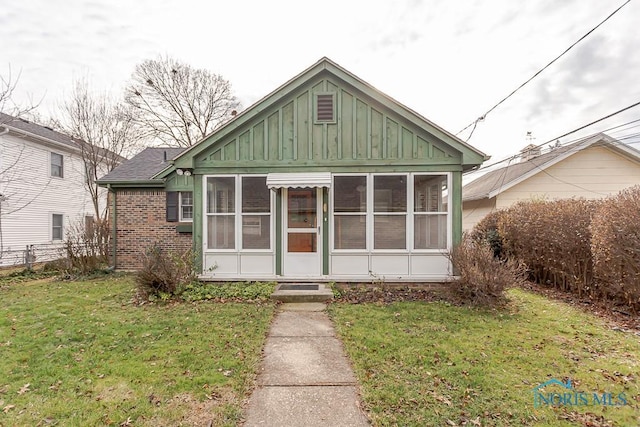 bungalow-style home featuring a sunroom and a front lawn