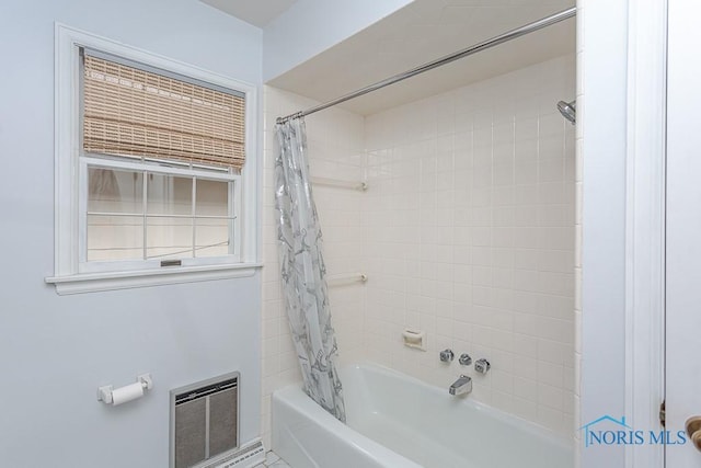 bathroom featuring heating unit and shower / bath combo with shower curtain