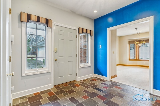 carpeted foyer entrance with a notable chandelier