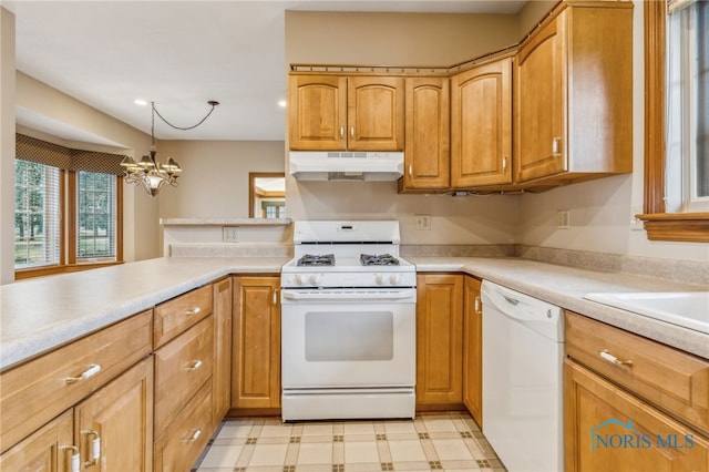 kitchen with kitchen peninsula, pendant lighting, a chandelier, and white appliances