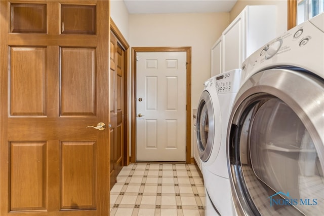 laundry area with washer and clothes dryer and cabinets