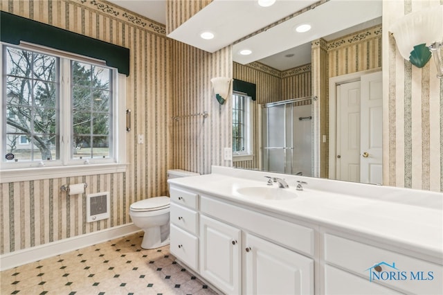 bathroom with vanity, heating unit, toilet, and a shower with door