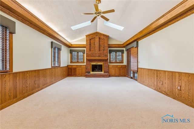 unfurnished living room with ceiling fan, crown molding, vaulted ceiling, and a brick fireplace