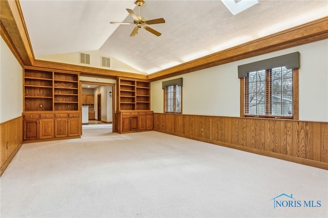 unfurnished living room with built in shelves, ceiling fan, light carpet, and lofted ceiling