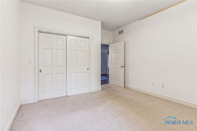 unfurnished bedroom featuring a closet and light colored carpet