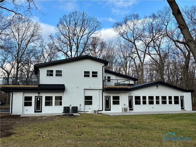 rear view of property featuring a lawn, a balcony, and central AC