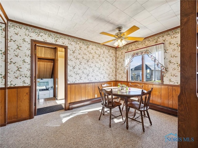 carpeted dining space with baseboard heating, ornamental molding, and ceiling fan