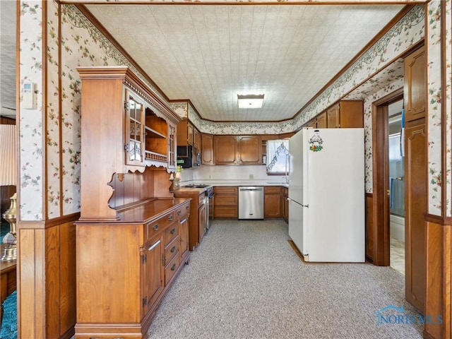 kitchen featuring ornamental molding, stainless steel appliances, and light carpet