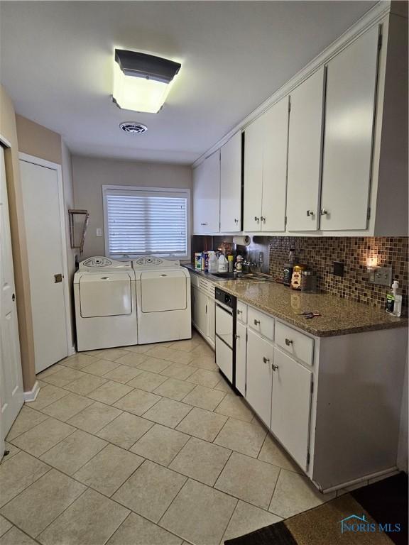 kitchen with washing machine and clothes dryer, tasteful backsplash, white cabinets, dark stone counters, and light tile patterned flooring