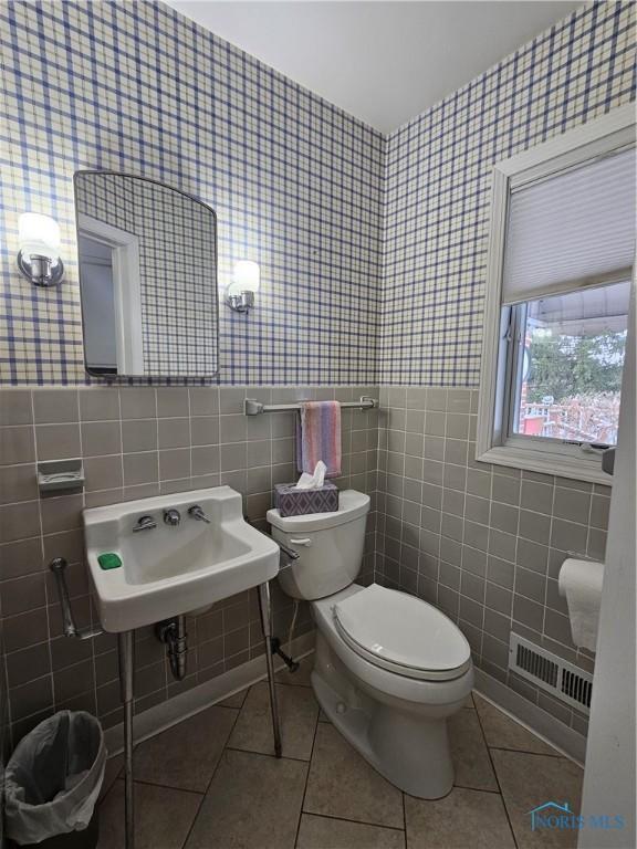 bathroom featuring tile patterned flooring, sink, toilet, and tile walls