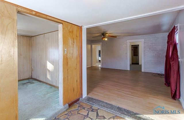 interior space with ceiling fan, brick wall, and wooden walls