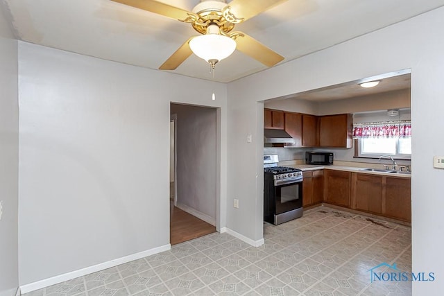 kitchen featuring ceiling fan, sink, stainless steel gas range, and wall chimney exhaust hood