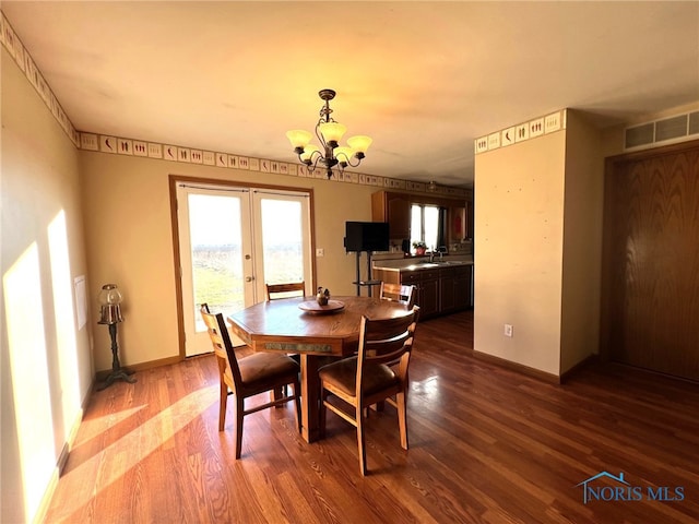 dining room with sink, dark hardwood / wood-style floors, a chandelier, and french doors