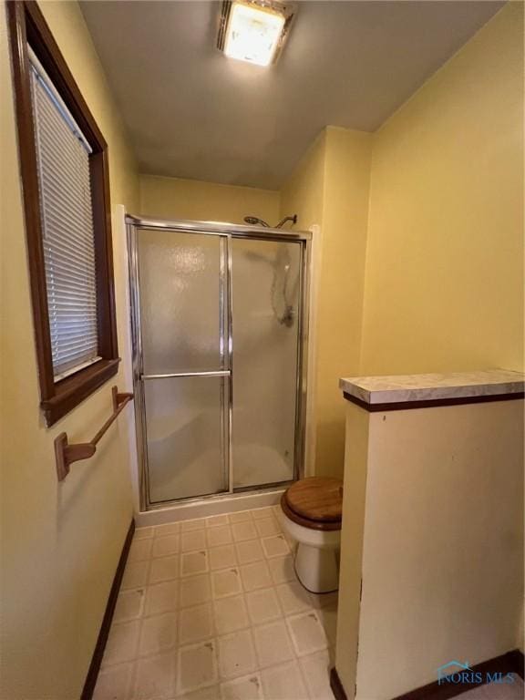 bathroom featuring toilet and a shower with shower door