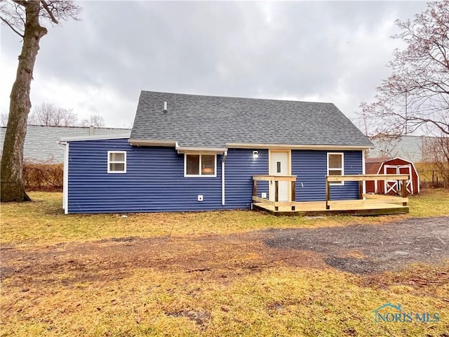 back of house with a deck and a storage shed