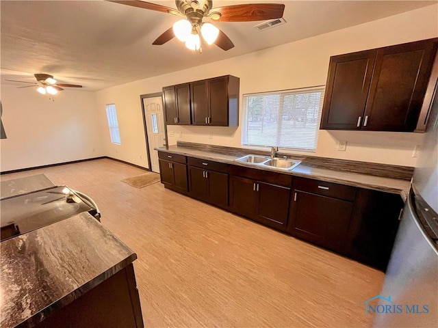 kitchen with dark brown cabinetry, ceiling fan, sink, and light wood-type flooring