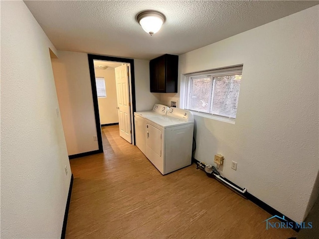 laundry area featuring washing machine and dryer, cabinets, a textured ceiling, and light hardwood / wood-style floors