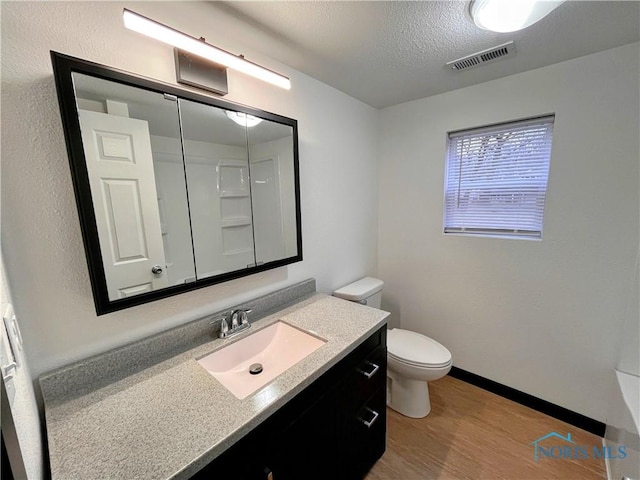 bathroom with hardwood / wood-style floors, vanity, a textured ceiling, and toilet