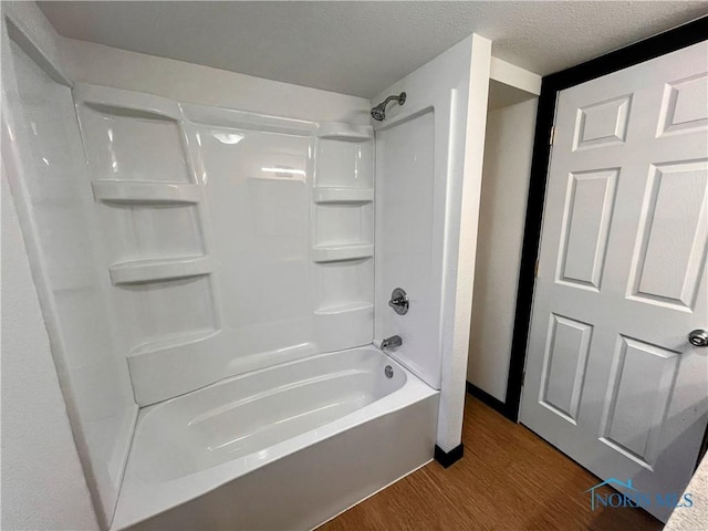 bathroom featuring hardwood / wood-style flooring, a textured ceiling, and bathtub / shower combination