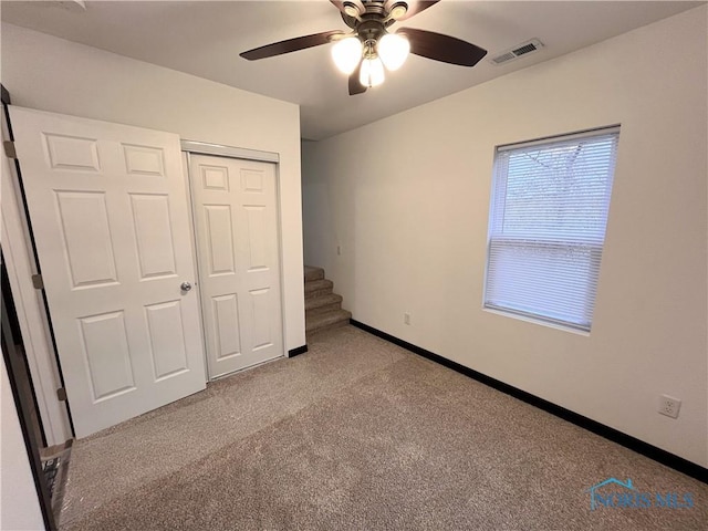 unfurnished bedroom featuring ceiling fan, a closet, and light colored carpet