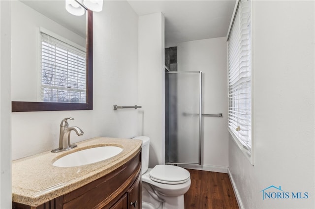 bathroom with hardwood / wood-style flooring, a shower with door, vanity, and toilet