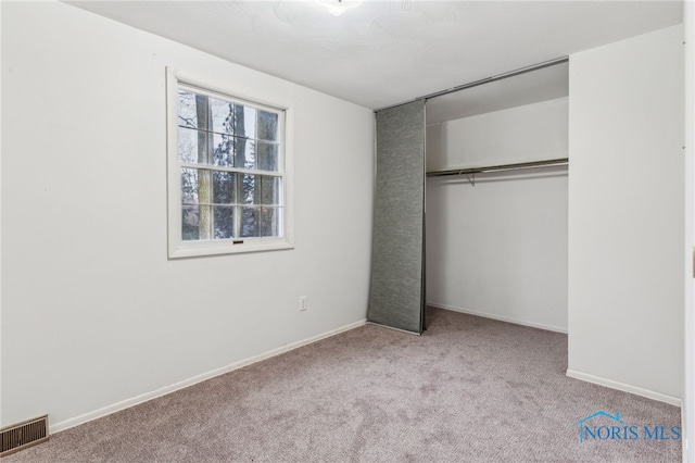 unfurnished bedroom featuring light carpet and a closet