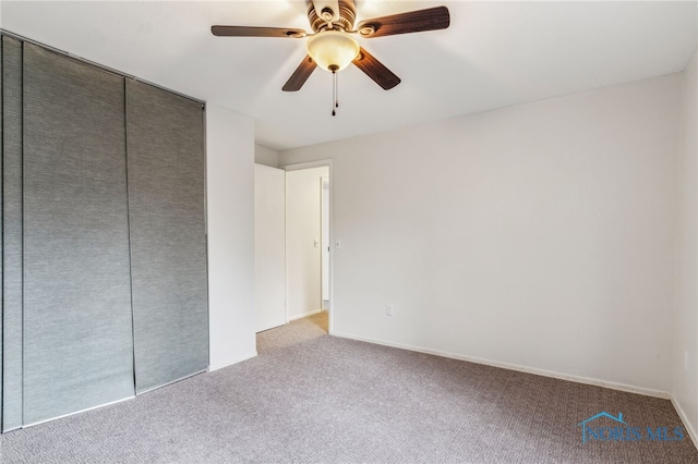 unfurnished bedroom with a closet, light colored carpet, and ceiling fan