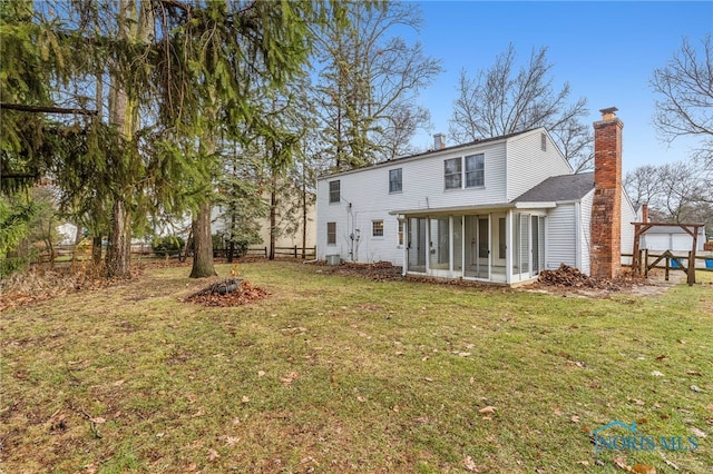 back of property with a sunroom and a yard