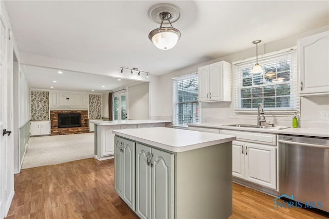 kitchen featuring a center island, white cabinetry, stainless steel dishwasher, and sink