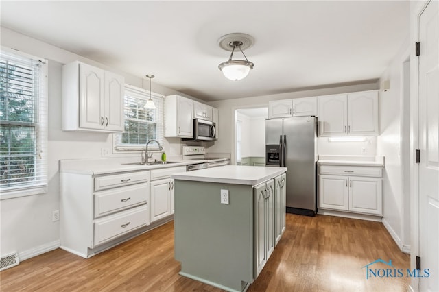 kitchen with a center island, white cabinets, stainless steel appliances, and decorative light fixtures