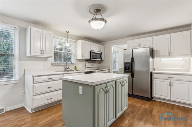 kitchen featuring appliances with stainless steel finishes, sink, pendant lighting, white cabinets, and a center island