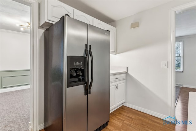 kitchen with white cabinets, stainless steel fridge, light hardwood / wood-style flooring, and crown molding