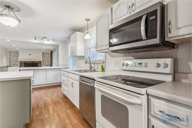 kitchen featuring sink, stainless steel appliances, light hardwood / wood-style flooring, decorative light fixtures, and white cabinets