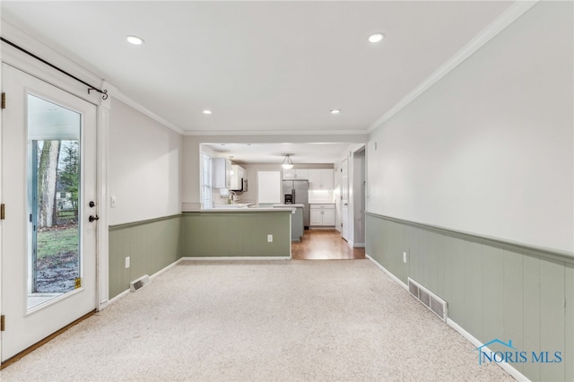 unfurnished living room featuring carpet flooring, ornamental molding, and sink