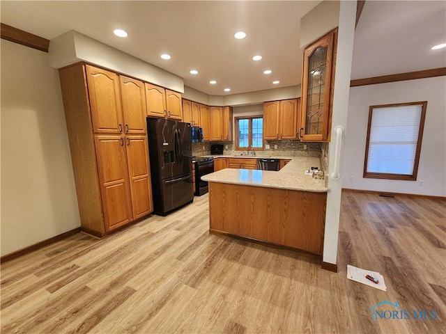 kitchen featuring kitchen peninsula, backsplash, ornamental molding, black appliances, and light hardwood / wood-style floors