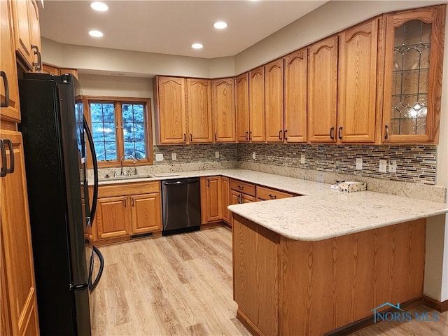 kitchen with sink, light hardwood / wood-style flooring, stainless steel dishwasher, kitchen peninsula, and black refrigerator