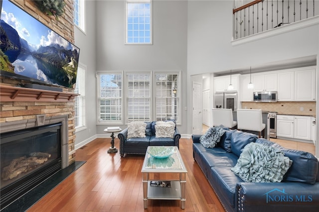 living room with a fireplace, a high ceiling, and light hardwood / wood-style flooring