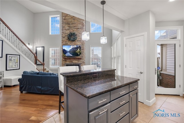 kitchen featuring a center island, dark stone countertops, a towering ceiling, pendant lighting, and a breakfast bar