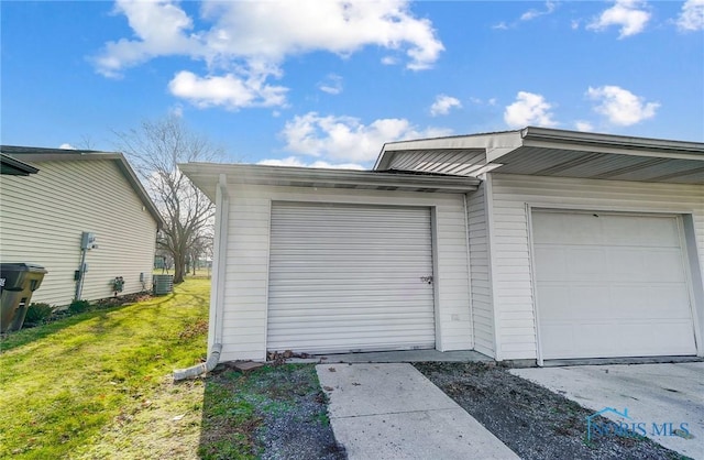 garage with central air condition unit and a lawn