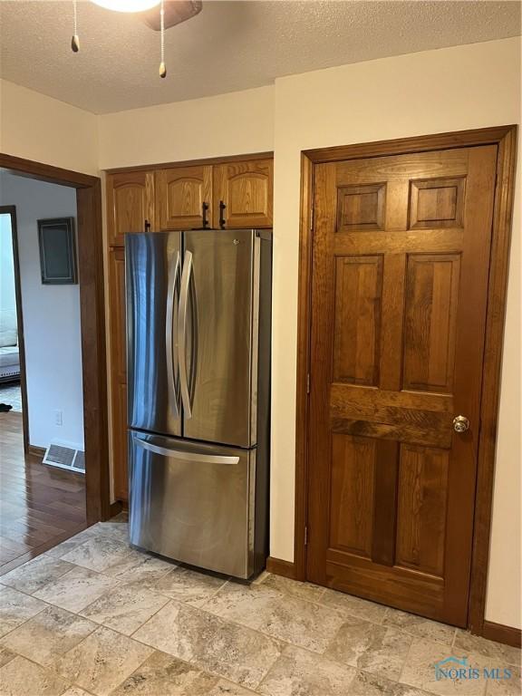 kitchen featuring a textured ceiling and stainless steel refrigerator