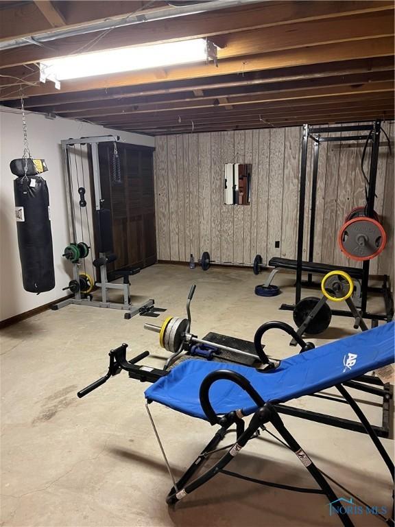 workout room featuring electric panel and wooden walls