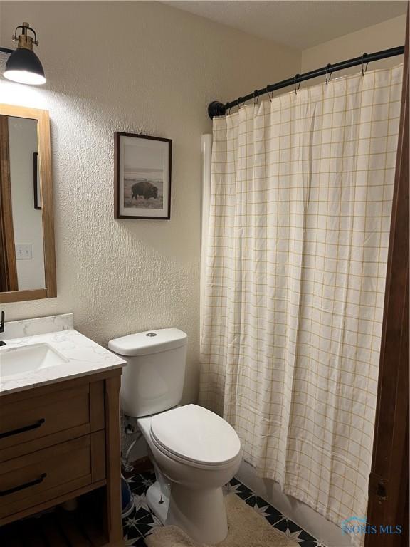 bathroom with a shower with curtain, vanity, toilet, and tile patterned floors