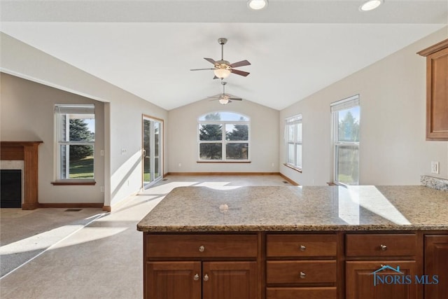 kitchen featuring light stone countertops, vaulted ceiling, plenty of natural light, and ceiling fan