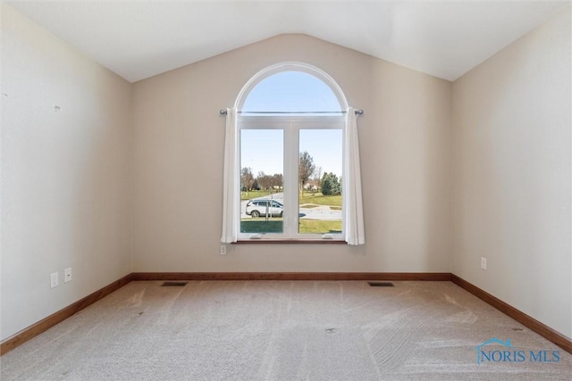 carpeted empty room featuring vaulted ceiling