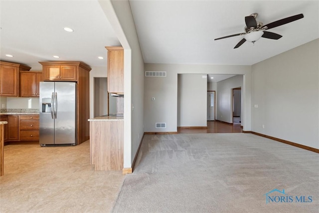 kitchen with ceiling fan, light colored carpet, light stone countertops, and stainless steel refrigerator with ice dispenser