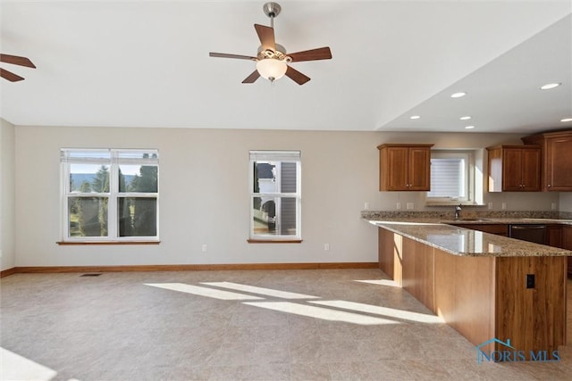 kitchen featuring light stone counters, sink, and ceiling fan