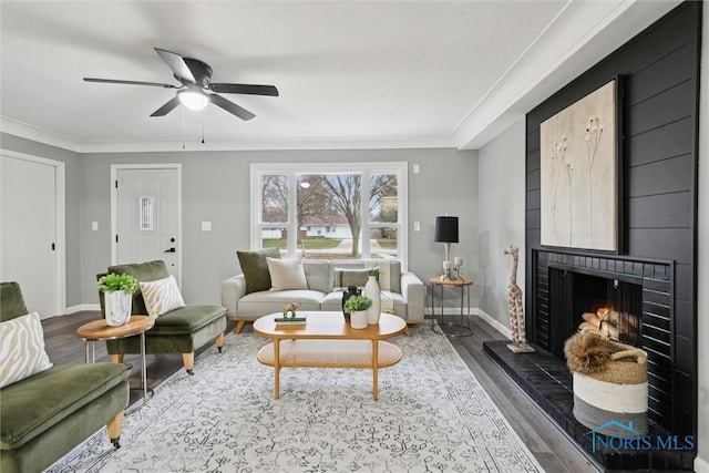 living room featuring ceiling fan, a fireplace, ornamental molding, and hardwood / wood-style flooring