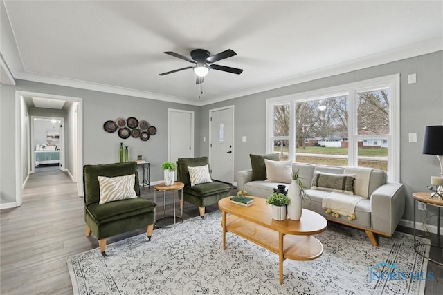 living room with crown molding, ceiling fan, and light wood-type flooring