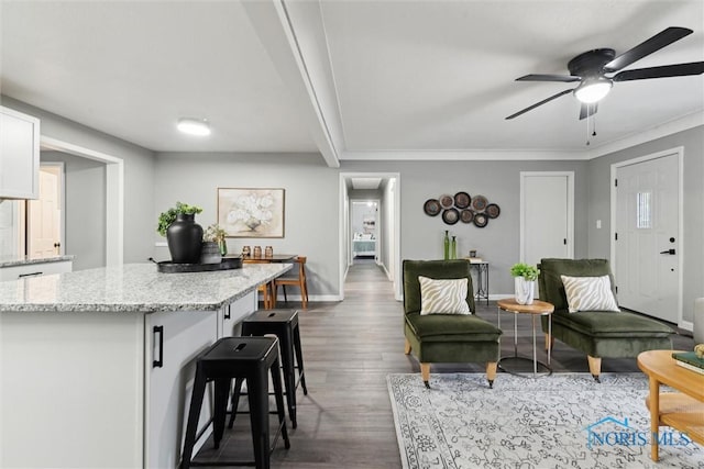 living room with crown molding, ceiling fan, and dark wood-type flooring